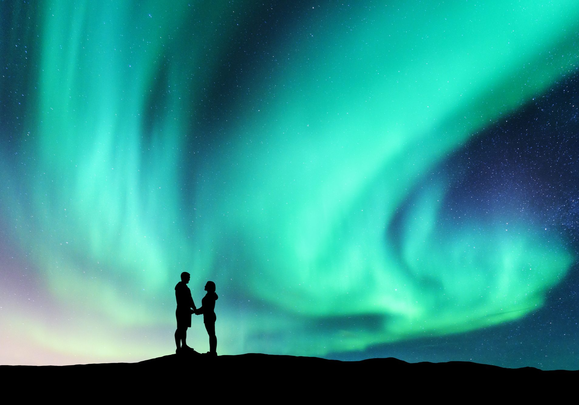 Northern lights and hugging couple on the hill. Landscape with night starry sky, aurora borealis, silhouette of man and woman. People. Concept background with Lovers and polar lights. Nature. Travel Northern lights and hugging couple on the hill. Landscape with night starry sky, aurora borealis, silhouette of man and woman. People. Concept background with Lovers and polar lights. Nature. Travel